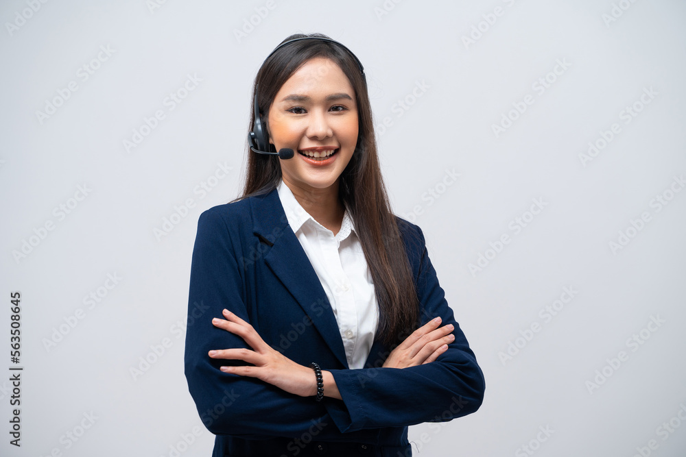 Beautiful Asian call center operator wearing a headset and microphone standing with her arms crossed isolated on grey background. Beautiful Asian call center operator wearing a headset and microphone standing with her arms crossed isolated on grey background.