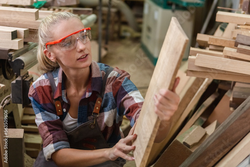 young carpenter woman wear uniform and goggles choose the size and quality wood used for work. craftsman professional concept. woodworking industry.