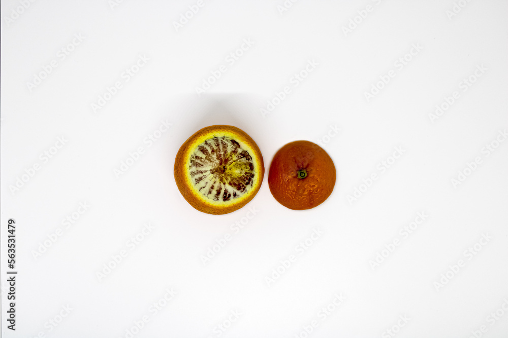 One blood orange with peeled off top next to it on white background