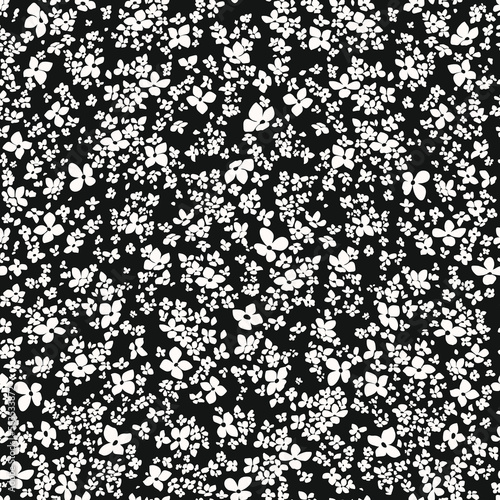 Hand Drawn small white flower in a dark background.Trendy liberty style seamless pattern, a lot of different flowers on the blooming field. Millefleurs background for fashion prints, textile, walpaper
