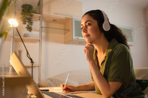 Videocall and online communication. Caucasian young woman wearing headphones working at laptop. Student learning in home. Concept of remote work and freelance