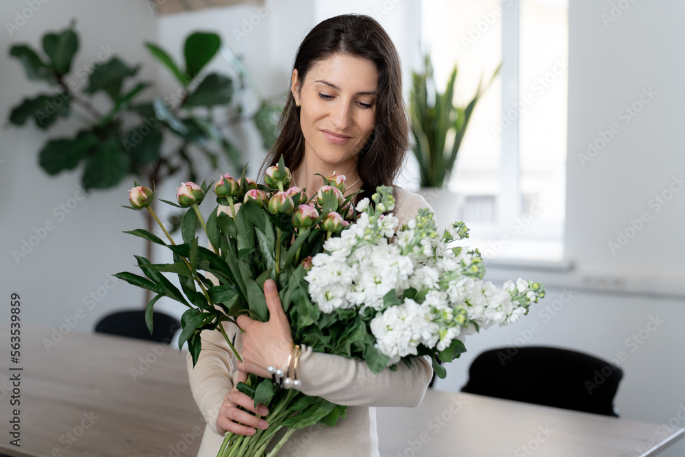 Positive woman holding a huge bouquet of flowers in her office. Birthday present smile. Positive woman holding a huge bouquet of flowers in her office. Birthday present smile.