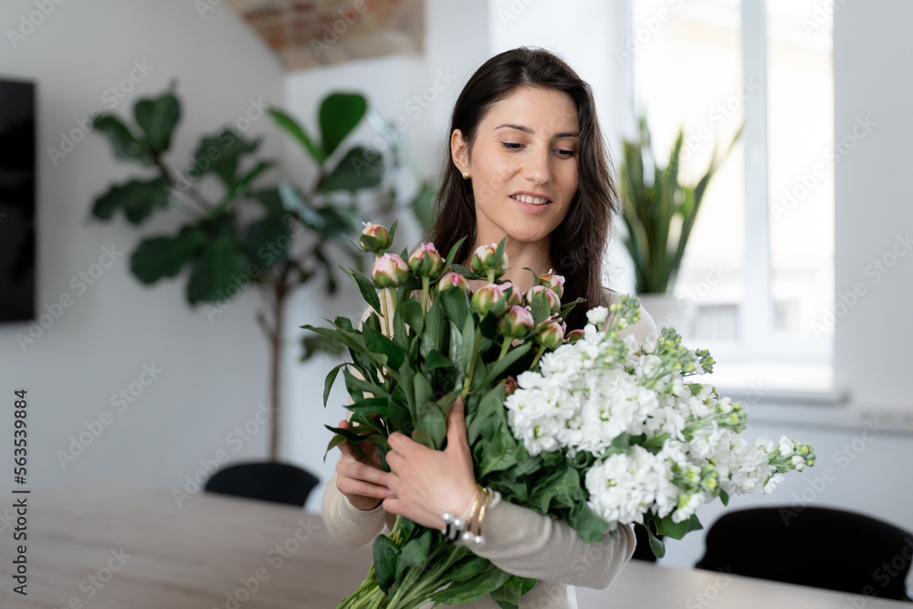 Positive woman holding a huge bouquet of flowers in her office. Birthday present smile. Positive woman holding a huge bouquet of flowers in her office. Birthday present smile.