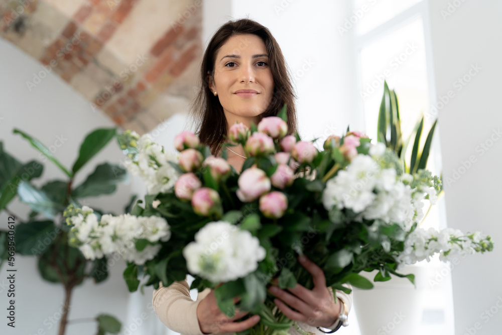 Positive woman holding a huge bouquet of flowers in her office. Birthday present smile. Positive woman holding a huge bouquet of flowers in her office. Birthday present smile.