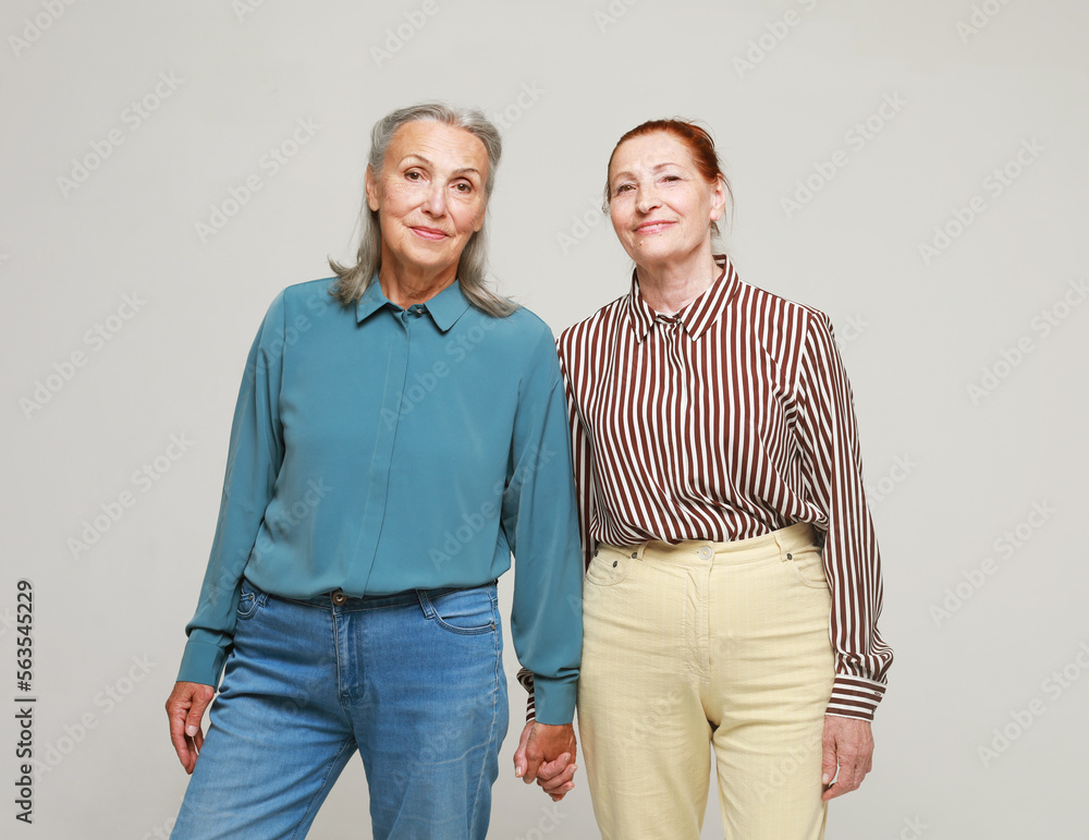 Two pretty old women friends on grey background. Two pretty old women friends on grey background.
