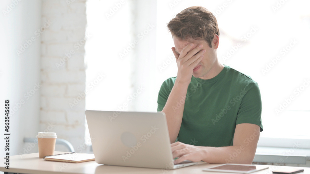 Young Man Reacting to Loss While Working in Office Young Man Reacting to Loss While Working in Office