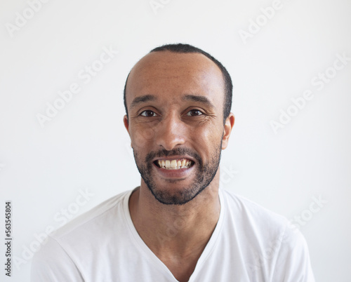A young unshaven man on a light gray background. African American.