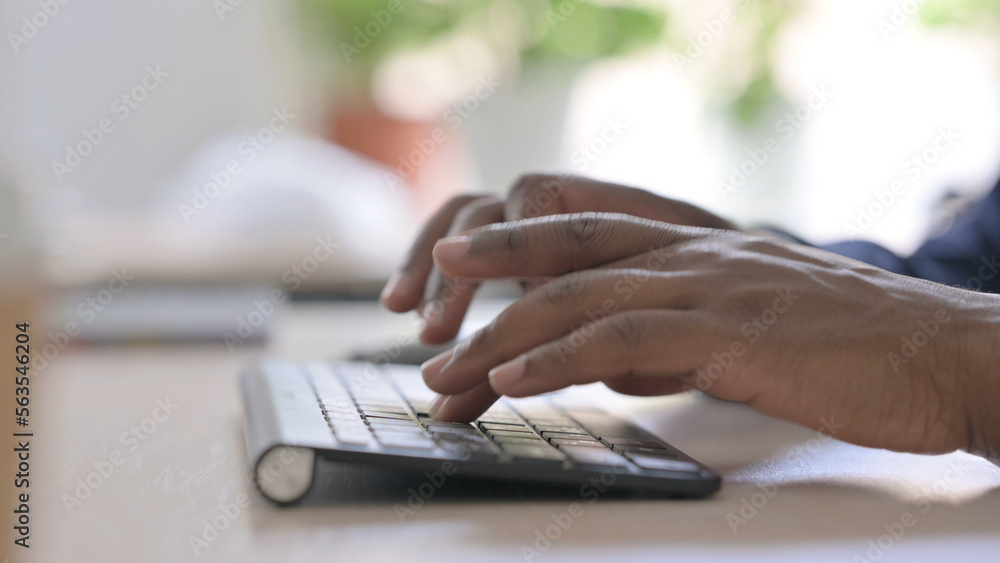 Side View of Young African Businessman Typing on Keyboard at Work Side View of Young African Businessman Typing on Keyboard at Work