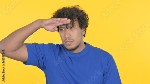 African Man Searching Opportunity on Yellow Background