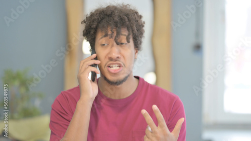 Upset African Man Talking on Phone in Anger