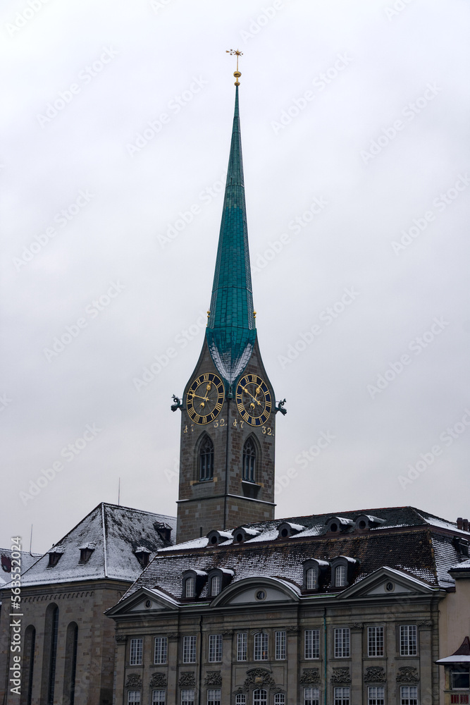 Snow covered church tower of protestant church Women's Minster at the medieval old town of Zürich on a snowy gray clouded alte autumn day. Photo taken December 16th, 2022, Zurich, Switzerland.