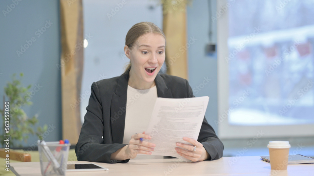 Businesswoman Celebrating Success while Reading Documents in Office Businesswoman Celebrating Success while Reading Documents in Office
