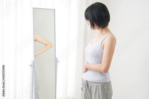 鏡で体型をチェックする女性