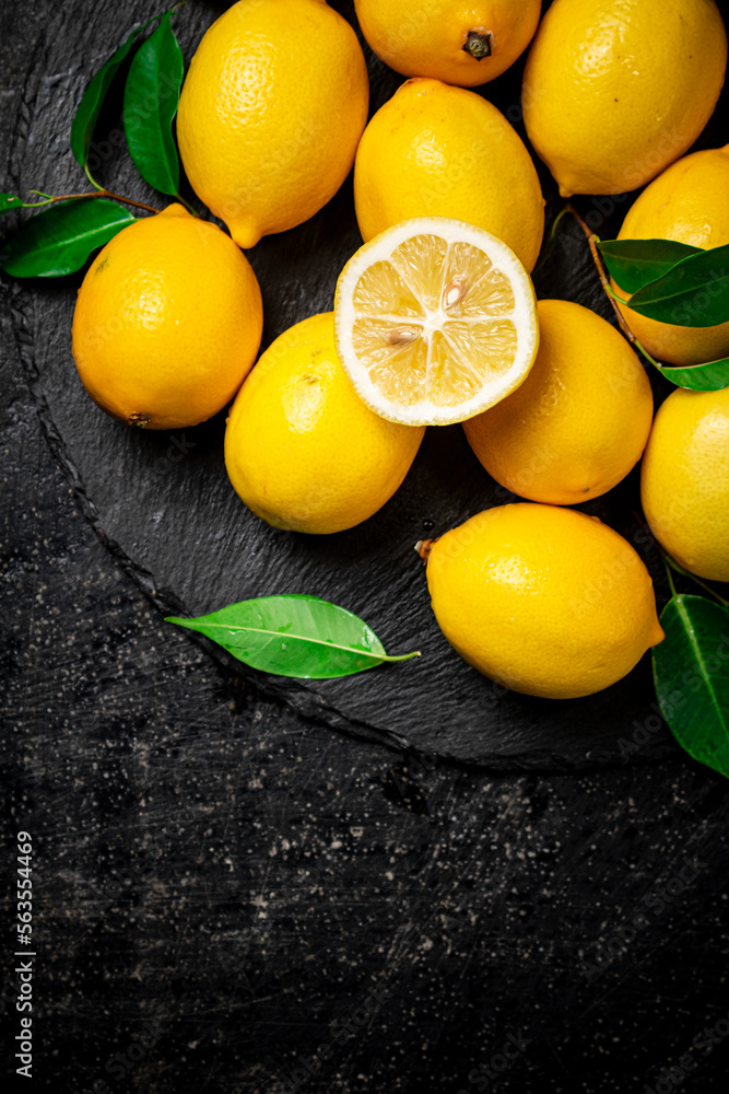 Juicy lemons with leaves on a stone board. 