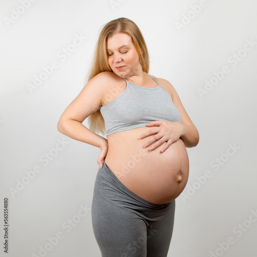 A pregnant girl, on a gray background. Big stomach, back pain. Free Download A pregnant girl, on a gray background. Big stomach, back pain. - GFXLoad