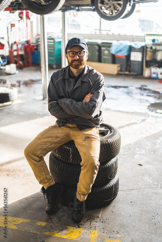A man sitting on a stack of car wheels in a modern and well-equipped car repair shop. High-quality photo