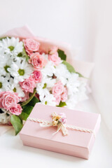 Beautiful bouquet of rose and chrysanthemums flowers and pink gift box on white table background. Gift for holiday, birthday, Wedding, Mother's Day, Valentine's day, Women's Day. Floral arrangement.