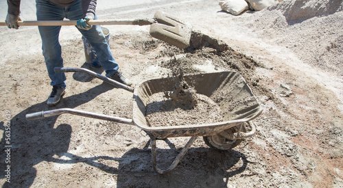 Worker prepare concrete with shovel at construction site.