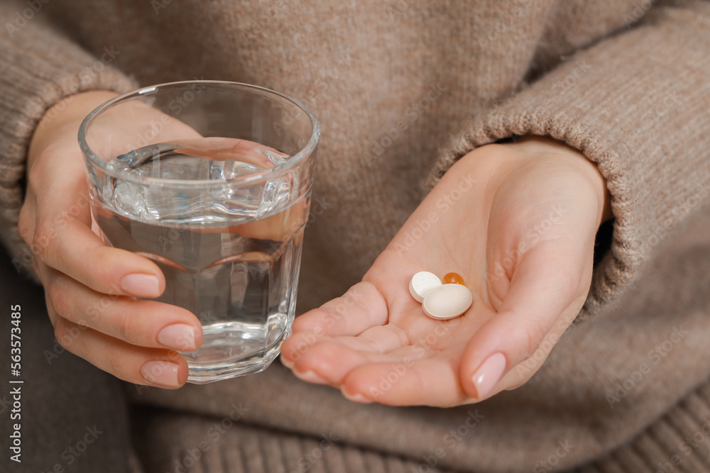 Woman with glass of water and pills, closeup Woman with glass of water and pills, closeup