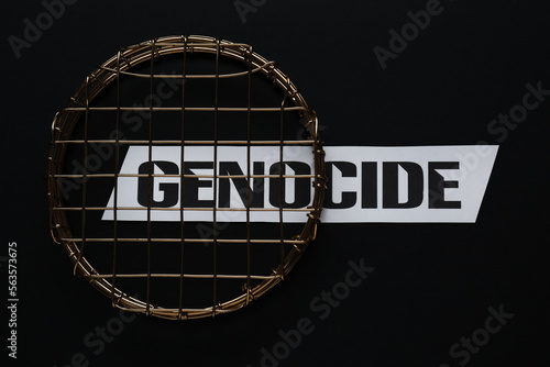 Word Genocide and golden decor with lattice on black background, flat lay photo