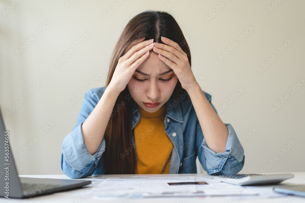 Young Asian woman looking at credit card invoice in her hands and worry about cash on bills payday Young Asian woman looking at credit card invoice in her hands and worry about cash on bills payday