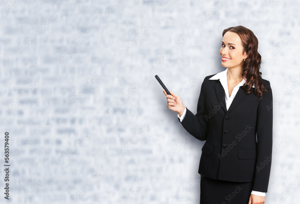 Portrait image of smiling beautiful business woman in confident suit, showing pointing advertising, white bricks wall background. Businesswoman, executive office worker, teacher gesturing Portrait image of smiling beautiful business woman in confident suit, showing pointing advertising, white bricks wall background. Businesswoman, executive office worker, teacher gesturing