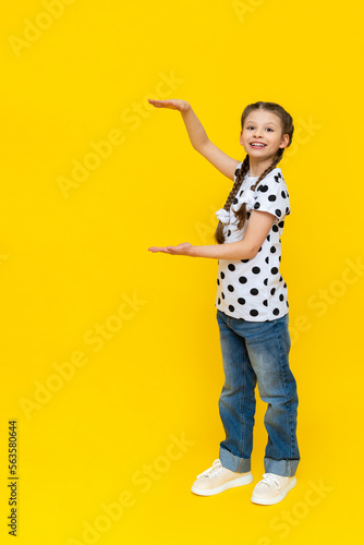 An attractive girl points to the advertisement and smiles, beautiful fashionable clothes on the child.