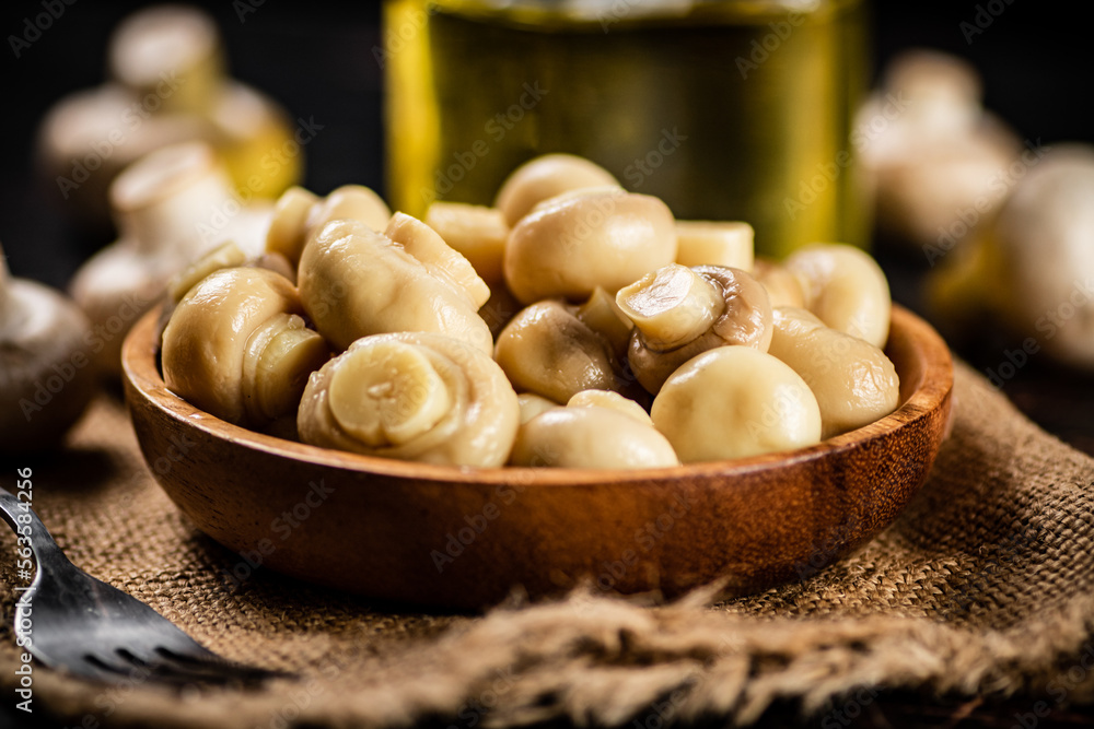 Wooden plate on burlap with pickled mushrooms. Wooden plate on burlap with pickled mushrooms.