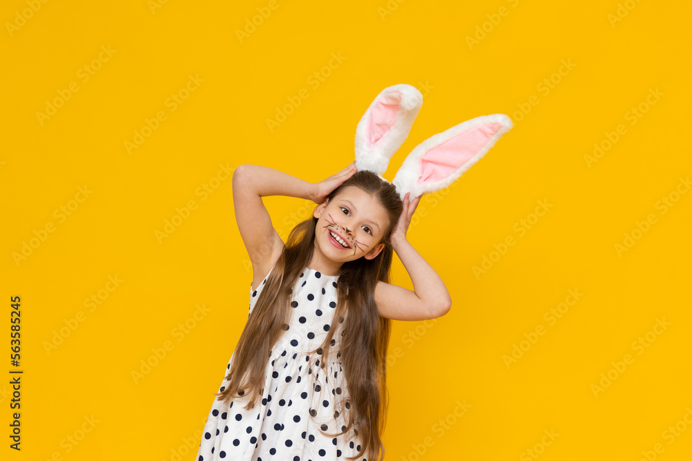 Masquerade Easter bunny ears on a beautiful little girl on a yellow isolated background. A girl with the face of an Easter bunny.