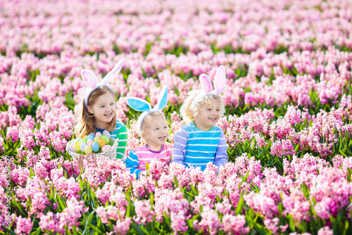 Kids on Easter egg hunt in blooming garden.