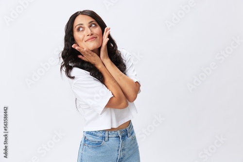 Woman in white t-shirt on white background brunette hands up gestures and signals poses in jeans emotion, lifestyle smiles, copy space