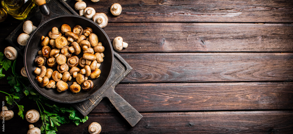 Fragrant homemade fried mushrooms in a frying pan on a cutting board. Fragrant homemade fried mushrooms in a frying pan on a cutting board.