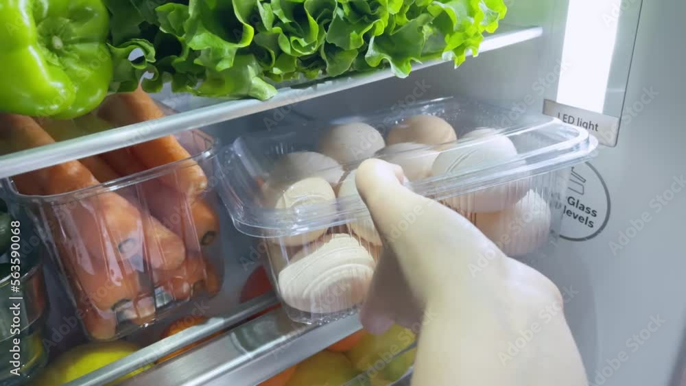 Woman puts eggs in fridge. Refrigerator full of food.Healthy eating