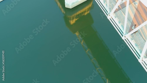 tilt aerial footage of the rippling green waters of the Cumberland River and the John Seigenthaler Pedestrian Bridge with winter trees and blue sky in Nashville Tennessee USA photo