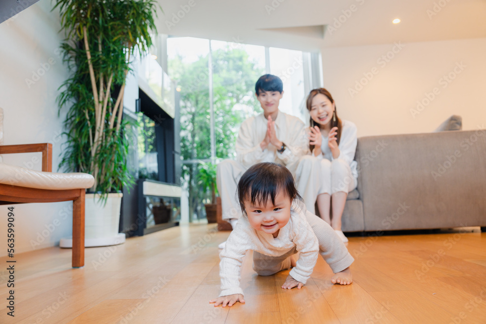 ハイハイをする赤ちゃんと子供の成長を見守る両親 ハイハイをする赤ちゃんと子供の成長を見守る両親