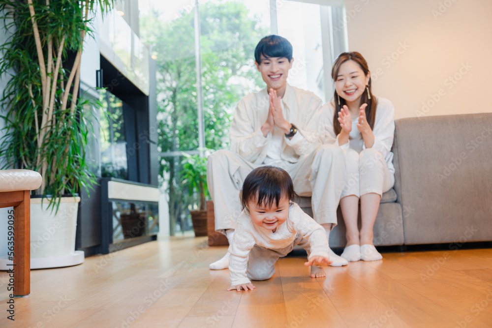 ハイハイをする赤ちゃんと子供の成長を見守る両親 ハイハイをする赤ちゃんと子供の成長を見守る両親