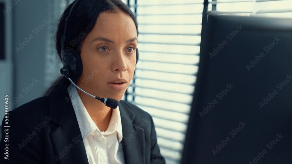Competent female operator working on computer and talking with clients ...