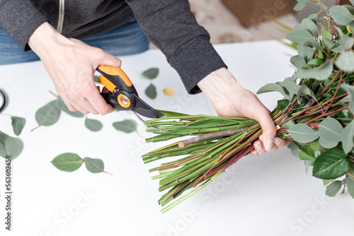 florist cuts the stems of flowers in a bouquet of pruning shears