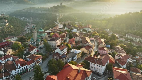 Flying over old houses, Ascension Cathedral and river in the canyon in Veliko Tarnovo. Aerial shot of sunny slightly foggy morning in Veliko Tarnovo, Bulgaria photo