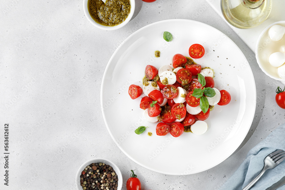 Caprese Salad with ripe tomatoes, mozzarella cheese, fresh basil, balsamic sauce, pesto on white plate. Healthy delicious diet salad. Caprese Salad with ripe tomatoes, mozzarella cheese, fresh basil, balsamic sauce, pesto on white plate. Healthy delicious diet salad.
