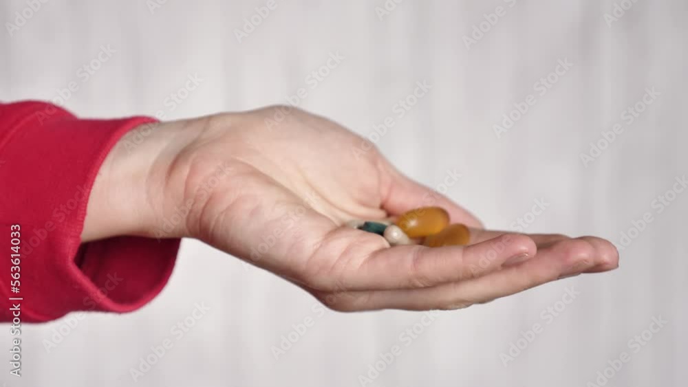 The female hand holds pills vitamins omega, spirulina, iron and is treated . Close-up and points your finger up. Nurse gives pills to the patient The female hand holds pills vitamins omega, spirulina, iron and is treated . Close-up and points your finger up. Nurse gives pills to the patient