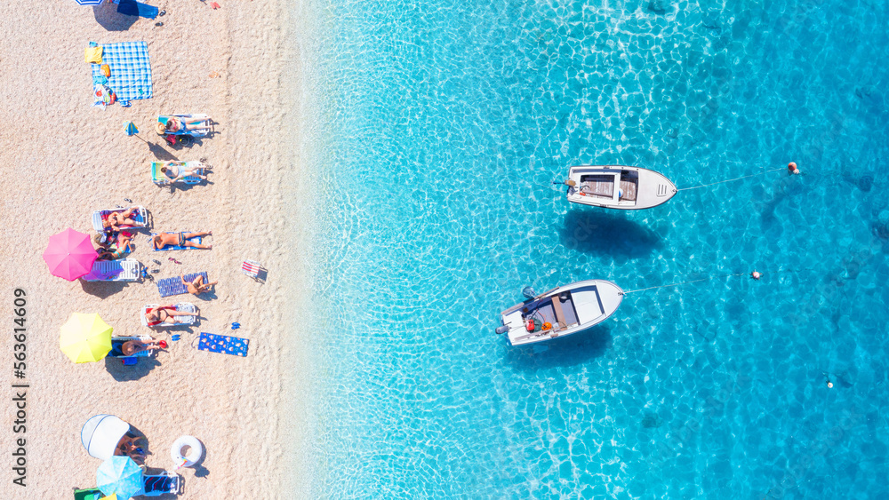Seascape with boats. Aerial view of floating boat on blue sea at sunny day. Aerial view on beach, pepole and umbrellas. Vacation time. Beach and blue water. Mediterranean sea.