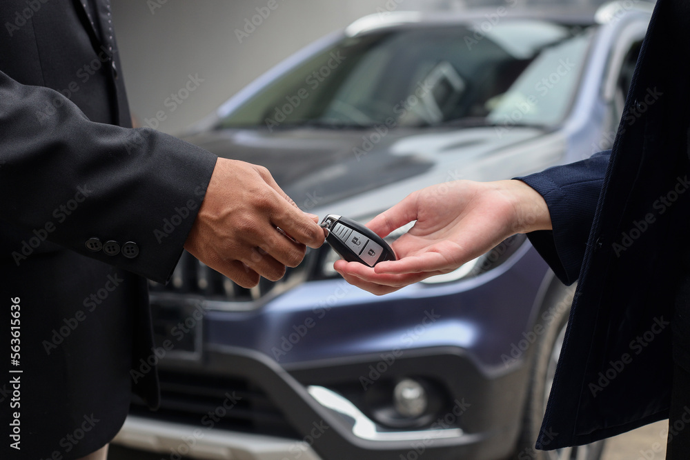 Close-up image of hands of client buys a car and receives keys from the car dealer sales.