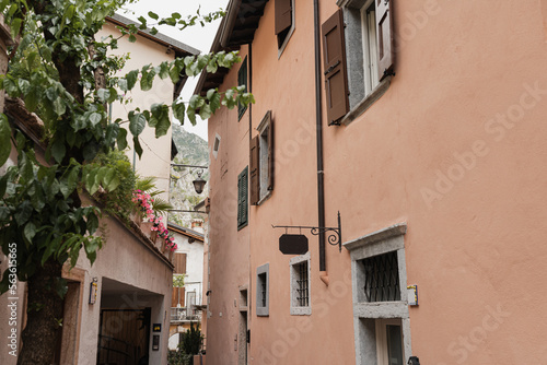 Rustic Italian architecture. Traditional historic European country buildings with wooden windows, flowers and blooming trees. Aesthetic summer vacation travel concept