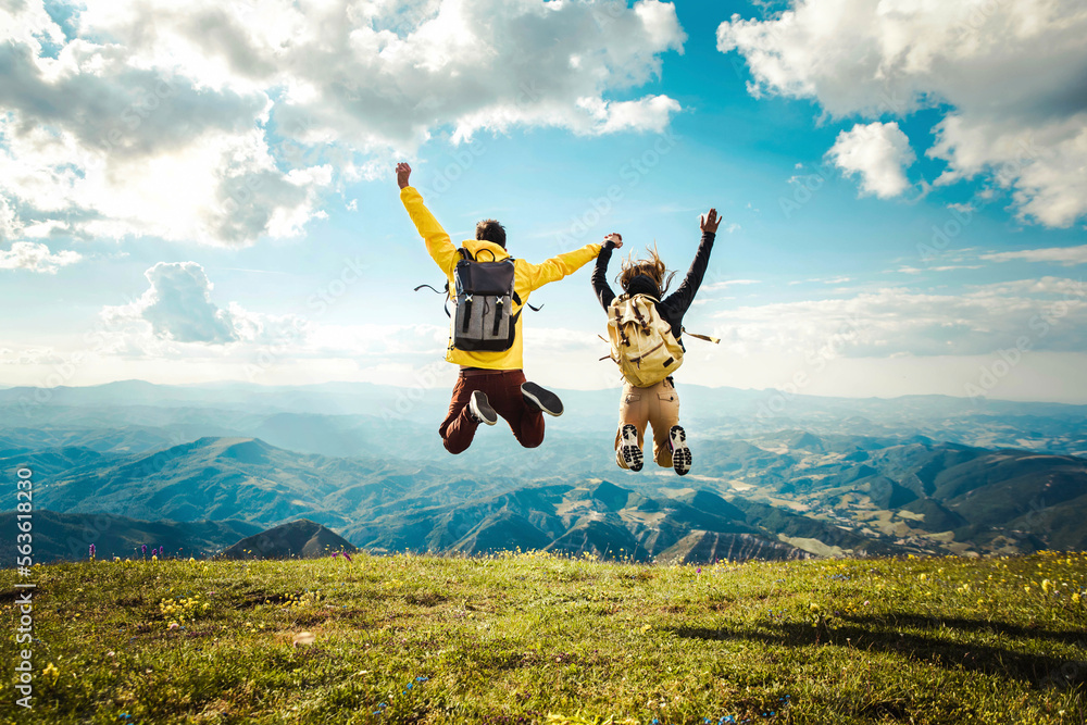 Hikers with backpack jumping with arms up on top of the mountain Stock ...