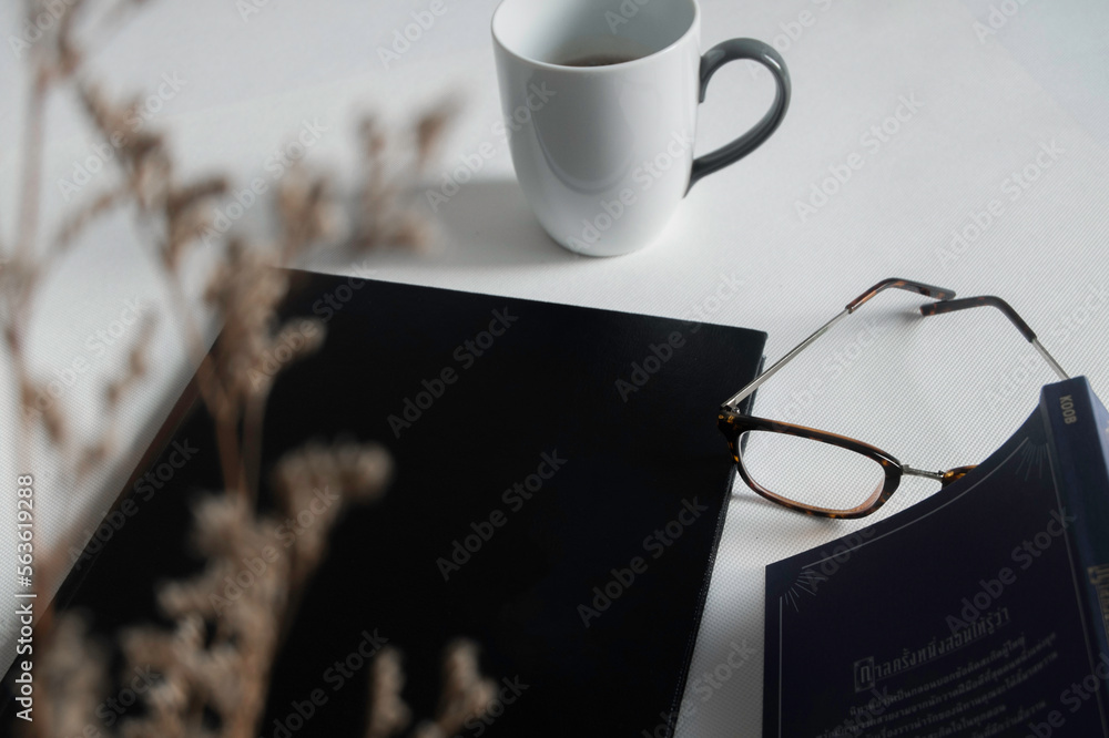 Top view of minimal workspace with blank screen , book, a cup of coffee, glasses, pen on white color desk Top view of minimal workspace with blank screen , book, a cup of coffee, glasses, pen on white color desk