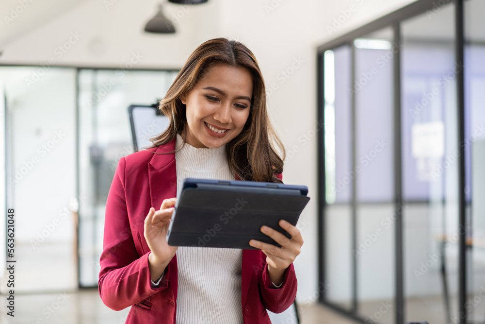 Young attractive female manager working on digital tablet while standing in modern office Young attractive female manager working on digital tablet while standing in modern office