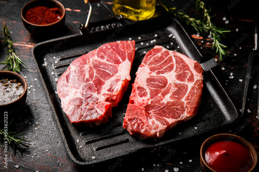 Raw steak pork in a grill pan with tomato sauce and spices. Raw steak pork in a grill pan with tomato sauce and spices.
