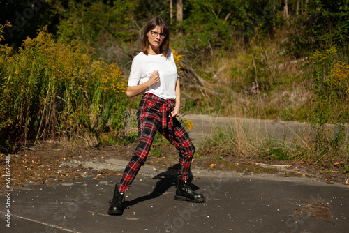 Portrait of woman 50plus in plaid pants and white t-shirt in forest