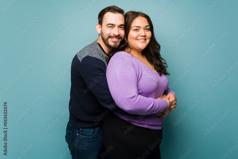 Obraz premium Happy couple of a big woman and a Caucasian man hugging in a studio